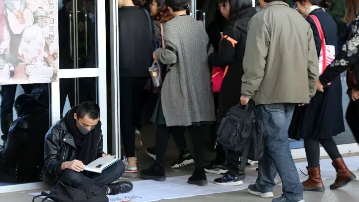 First day of Late performance with artist reading on white paper at gate